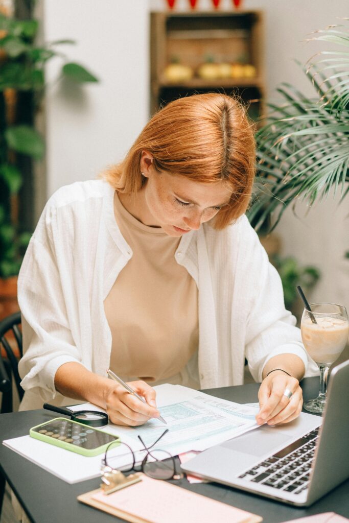 Une femme à son bureau vérifie un document, calculatrice à l'appui