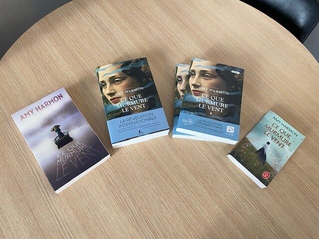 Photo représentant l'édition France Loisirs du titre Ce que murmure le vent, d'Amy Harmon, publiée en avant-première six mois avant l’édition Charleston ; l'édition Charleston (septembre 2021) ; l'édition gros caractères La Loupe (en deux volumes) publiée trois mois après l'édition Charleston ; l'édition poche du Livre de Poche, parue un an après (septembre 2022).